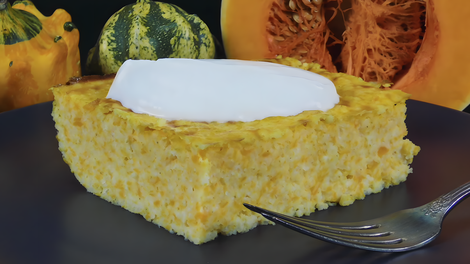 Кусочек запеканки из пшенной каши с тыквой со сметаной лежит на тарелке Кусочек запеканки из пшенной каши с тыквой со сметаной лежит на тарелке
