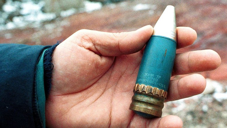 Член специальной группы держит 30-мм бронебойный снаряд с обедненным ураном, использовавшийся НАТО во время воздушных ударов по Боснии в 1995 году