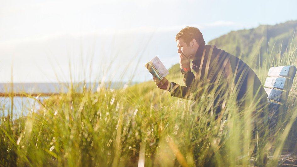 Мужчина-Овен читает книгу в парке Мужчина-Овен читает книгу в парке