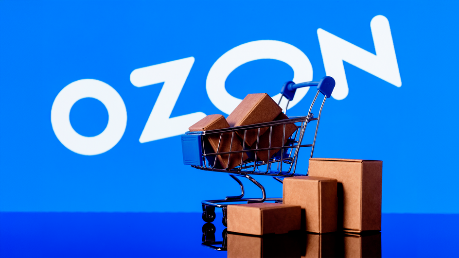 Тележка с коробками перед синим фоном с надписью Ozon Тележка с коробками перед синим фоном с надписью Ozon