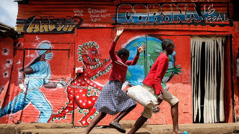 Дети играют на фоне граффити посвященном борьбе с коронавирусом в трущебах Кибера в пригороде Найроби, Кения