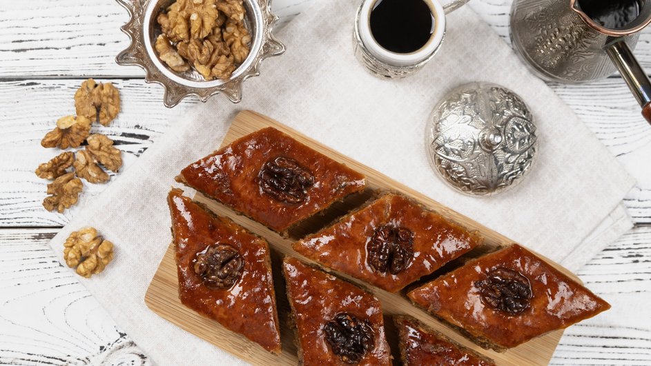Армянская пахлава на молоке лежит на доске рядом с орехами и кофе