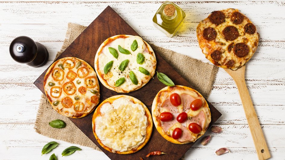 Мини-пицца разных вкусов лежит на столе Мини-пицца разных вкусов лежит на столе