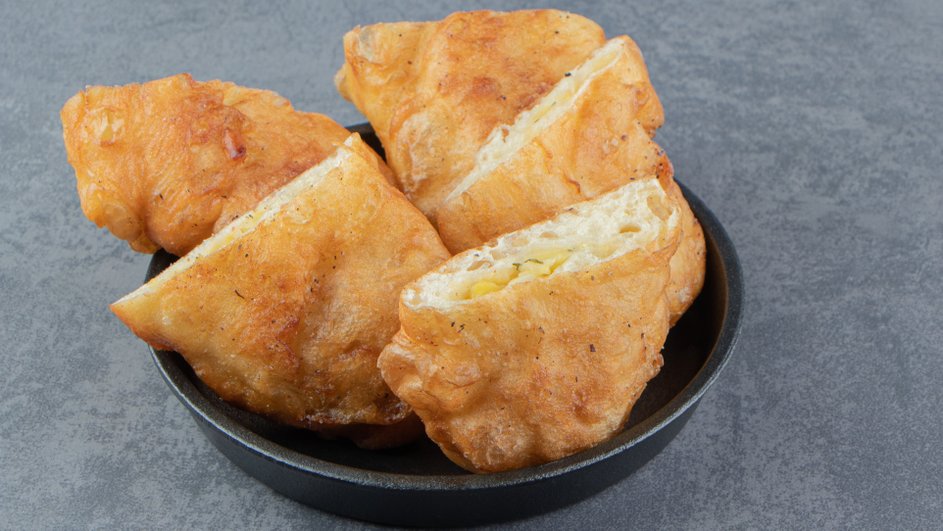 Постные пирожки с капустой, приготовленные на сковороде, лежат в тарелке