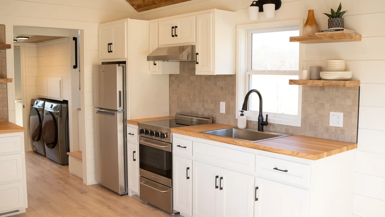 Кухня достаточно хорошо оборудована для крошечного дома и включает в себя холодильник с морозильной камерой, раковину, посудомоечную машину, варочную панель и шкафы.