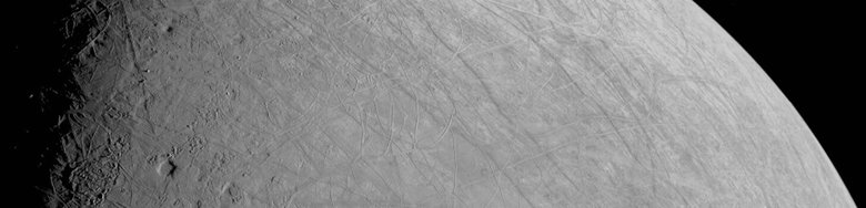 Так выглядит поверхность спутника Европа. Из-за повышенного контраста между светом и тенью вдоль терминатора (граница ночной стороны) легко различимы неровности рельефа, в том числе высокие блоки, отбрасывающие тень. Продолговатая яма рядом с терминатором может быть разрушенным ударным кратером. Фото: NASA/JPL-Caltech/SWRI/MSSS