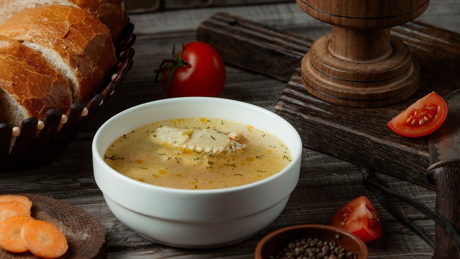 Щи с курицей, приготовленные в мультиварке, в глубокой тарелке стоят рядом с нарезанным хлебом, кусочками моркови, помидорами, чашей с горошинами перца и деревянной доской на деревянном столе Щи с курицей, приготовленные в мультиварке, в глубокой тарелке стоят рядом с нарезанным хлебом, кусочками моркови, помидорами, чашей с горошинами перца и деревянной доской на деревянном столе