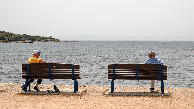 Мужчины беседуют на берегу моря в пригороде Глифада, недалеко от Афин, Греция