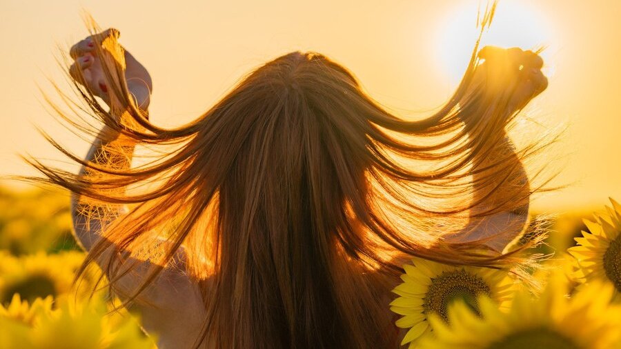 Девушка развивает волосы на фоне солнца 