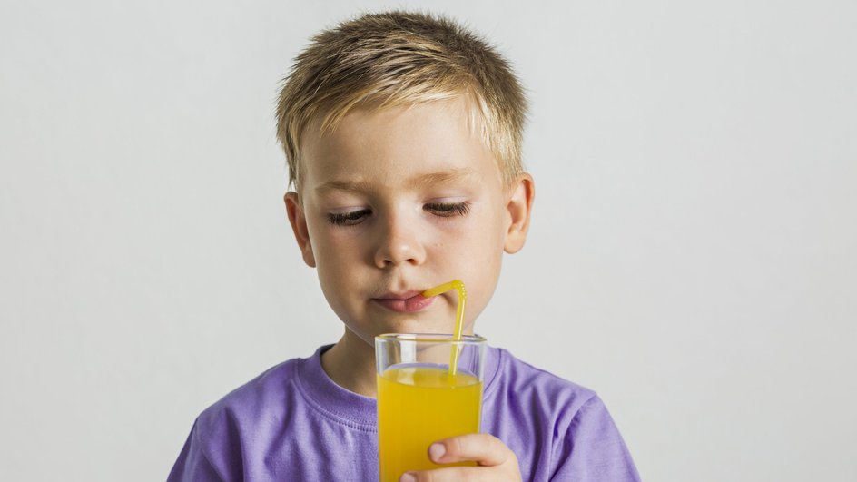 мальчик пьет апельсиновый сок через трубочку