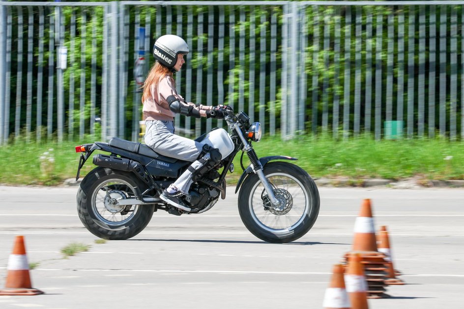 Девушка во время практических занятий по вождению мотоцикла в автошколе