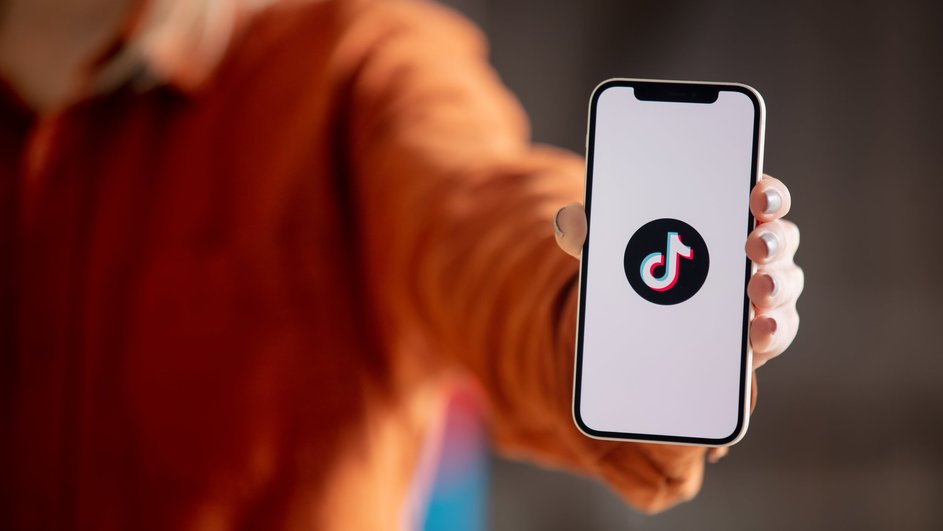 Девушка держит телефон, на котором горит иконка приложения TikTok