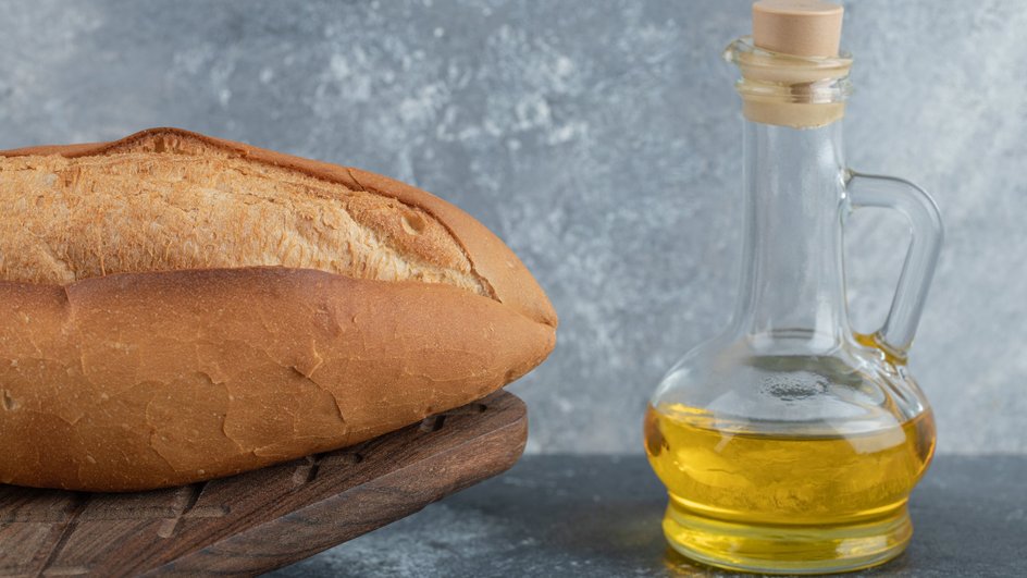 Бутылка с льняным маслом рядом с буханкой хлеба Бутылка с льняным маслом рядом с буханкой хлеба