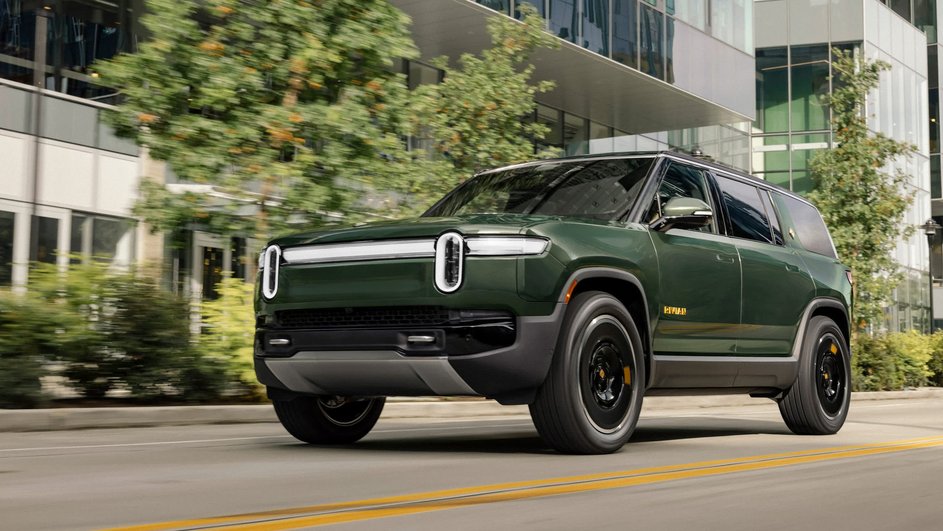 Зеленый кроссовер Rivian R1S едет по дороге города