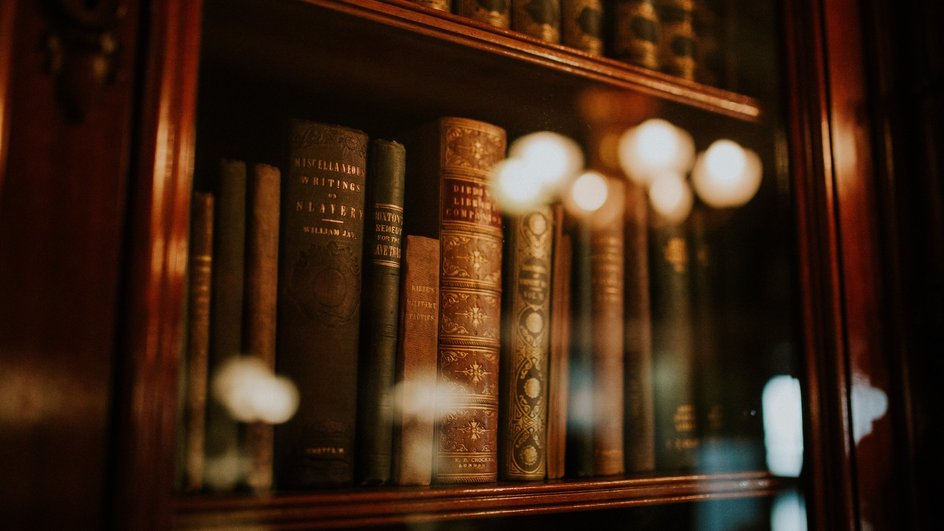 Старинные книги стоят в книжном шкафу