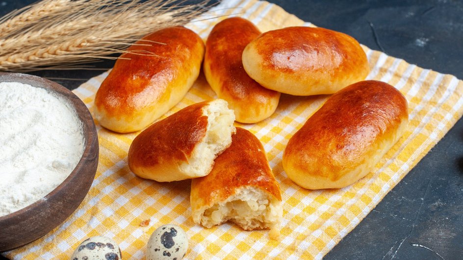 Пирожки на Масленицу лежат на столе рядом с мукой