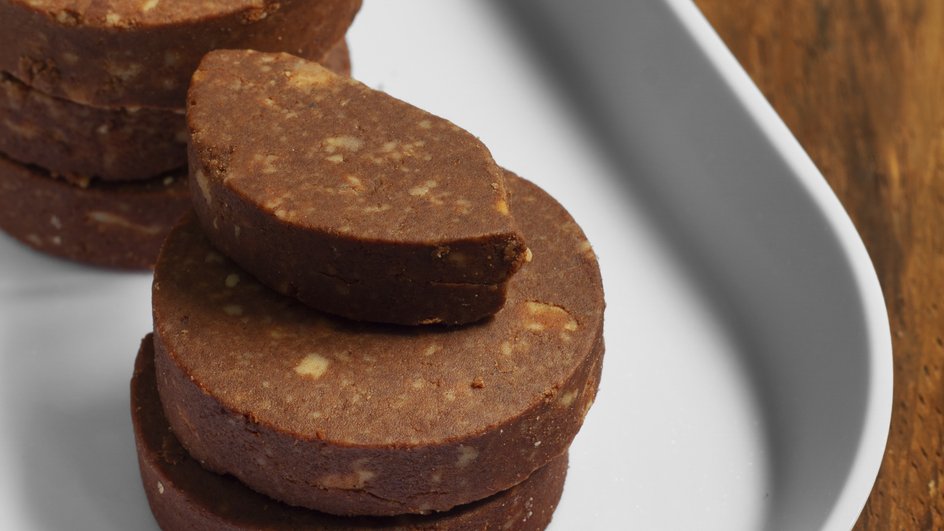 Кусочки шоколадной колбасы без орехов лежат на тарелке Кусочки шоколадной колбасы без орехов лежат на тарелке