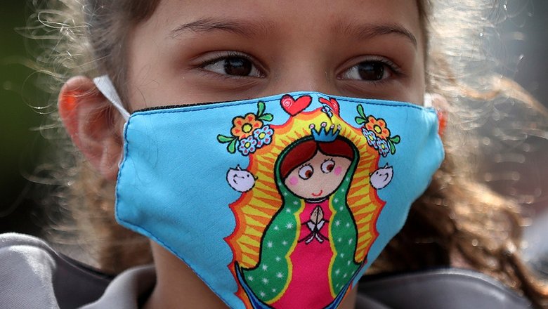 Венесуэльская девочка-мигрант в защитной маске с рисунком Девы Марии Гваделупской в лагере для мигрантов в Боготе, Колумбия
