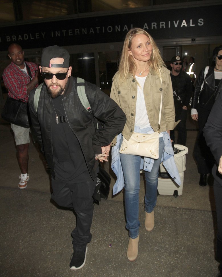 Кэмерон Диаз и ее супруг в аэропорту Лос-Анджелеса. Актриса прикрыла область живота сумочкой