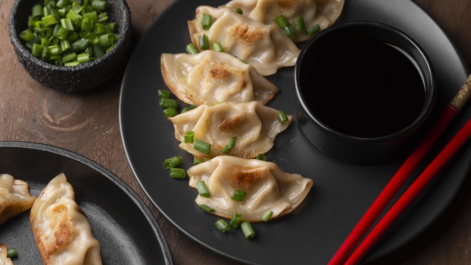 Пельмени с рыбой и кальмарами с хрустящей корочкой на черной посуде 