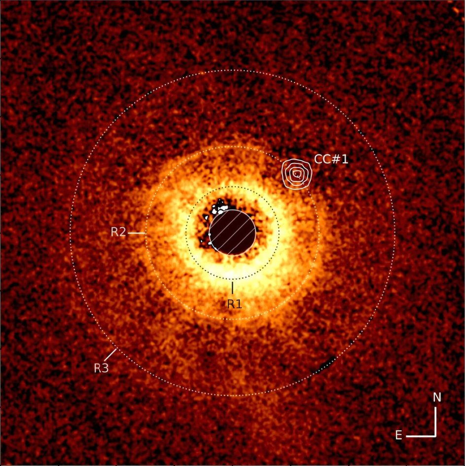 Диск вокруг звезды TWA 7, снятый с помощью инструмента SPHERE Очень Большого Телескопа ESO. На него наложено изображение, полученное с помощью инструмента MIRI JWST. В кольце R2 астрономы разглядели пустую область, где предположительно и вращается планета Диск вокруг звезды TWA 7, снятый с помощью инструмента SPHERE Очень Большого Телескопа ESO. На него наложено изображение, полученное с помощью инструмента MIRI JWST. В кольце R2 астрономы разглядели пустую область, где предположительно и вращается планета