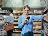 девушка выбирает продукты в магазине с телефоном девушка выбирает продукты в магазине с телефоном