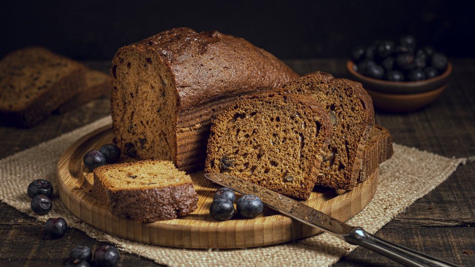 Постная чайная коврижка с медом и корицей лежит на доске рядом с ягодами