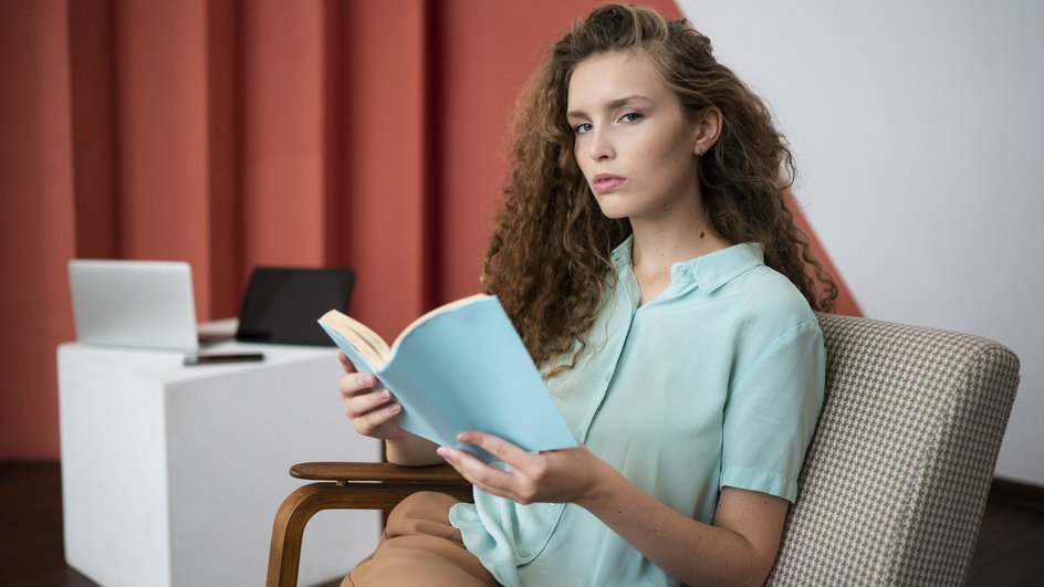 Девушка читает книгу о том, как справиться с тревогой и страхом неопределенности Девушка читает книгу о том, как справиться с тревогой и страхом неопределенности