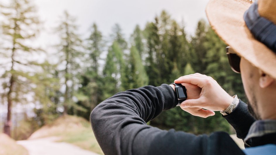 Мужчина смотрит на часы с функцией GPS-трекером Мужчина смотрит на часы с функцией GPS-трекером