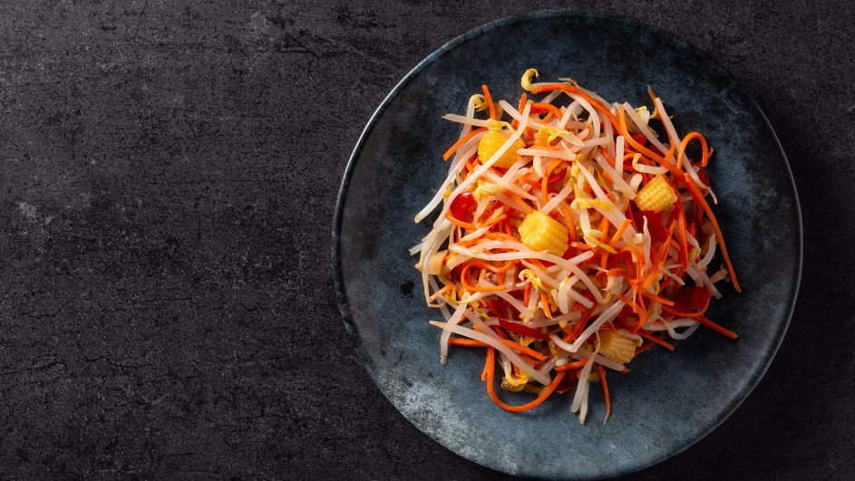 Салат с корейской морковью и кукурузой лежит на тарелке