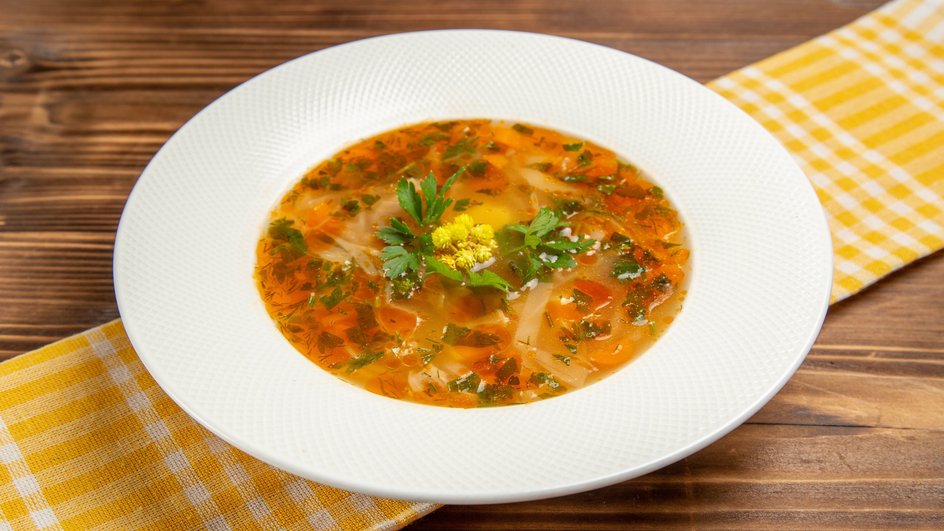 Тарелка рыбного супа с рисом и картофелем, приготовленого в мультиварке, стоит на столе