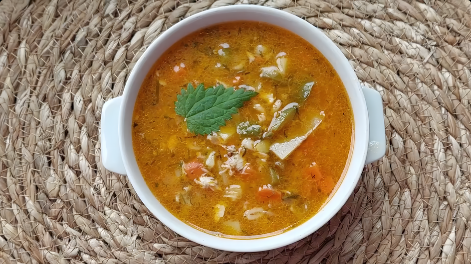 Тарелка супа с курицей и перловкой стоит на столе