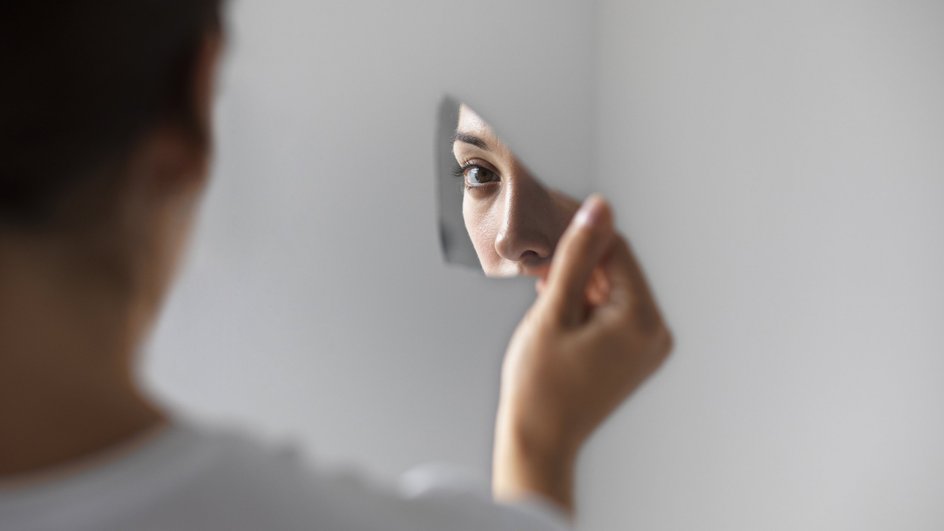 Девушка смотрит в разбитое зеркало 