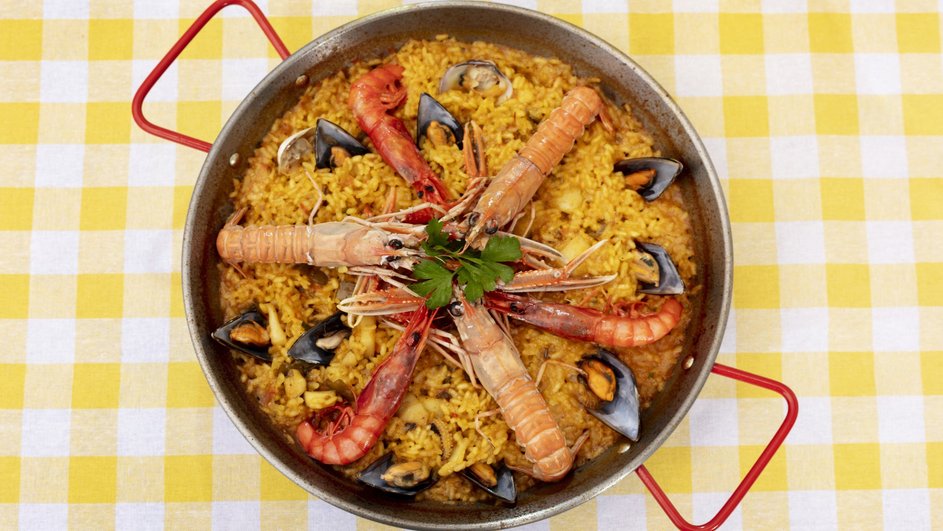 Кастрюля испанской паэльи с морепродуктами стоит на столе Кастрюля испанской паэльи с морепродуктами стоит на столе