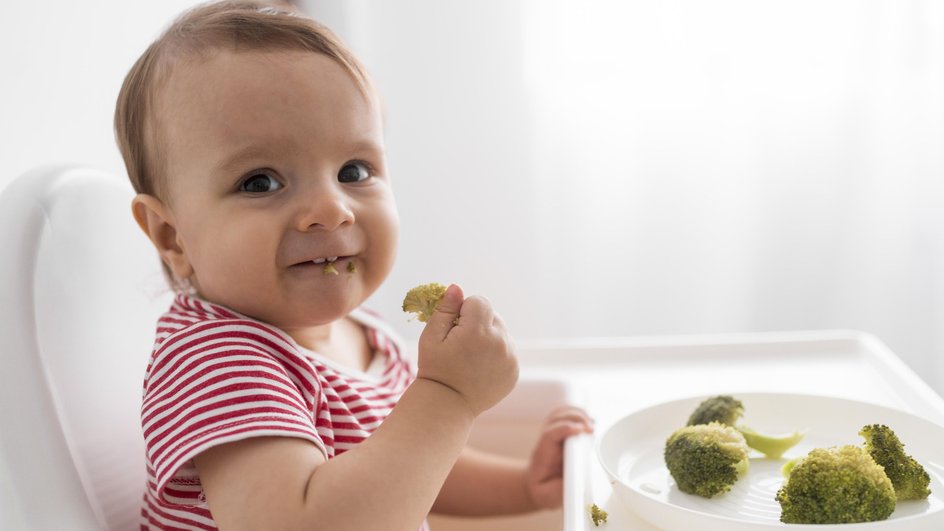 Малыш ест брокколи