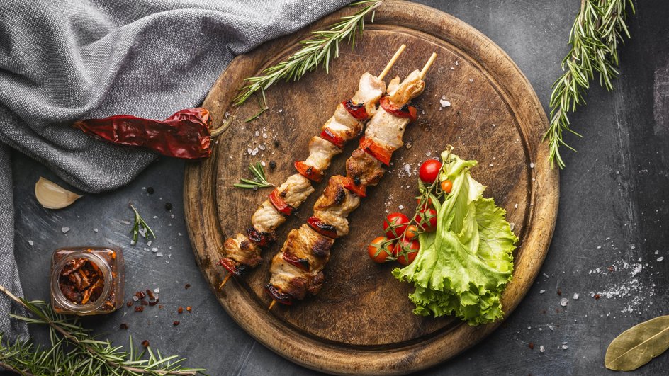 Шашлыки на шпажках из кусочков курицы и сладкого перца, выложенные на круглую деревянную доску Шашлыки на шпажках из кусочков курицы и сладкого перца, выложенные на круглую деревянную доску