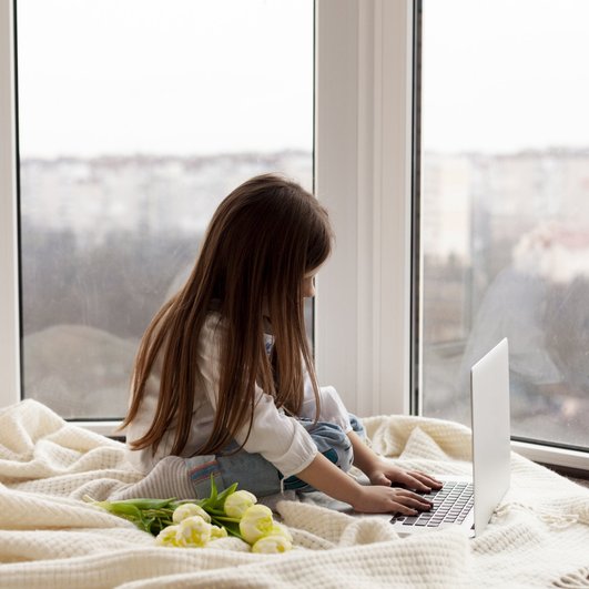 Девочка на утепленном балконе смотрит в ноутбук