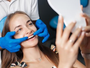 девушка устанавливает виниры у стоматолога