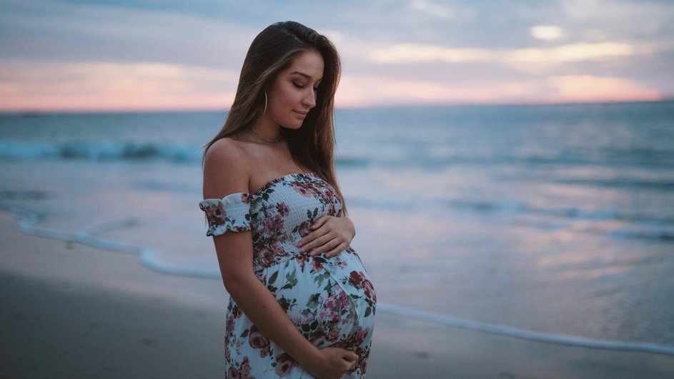 беременная женщина позирует на фоне океана