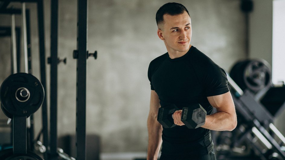 Мужчина-Овен занимается спортом и держит гантели в руках Мужчина-Овен занимается спортом и держит гантели в руках