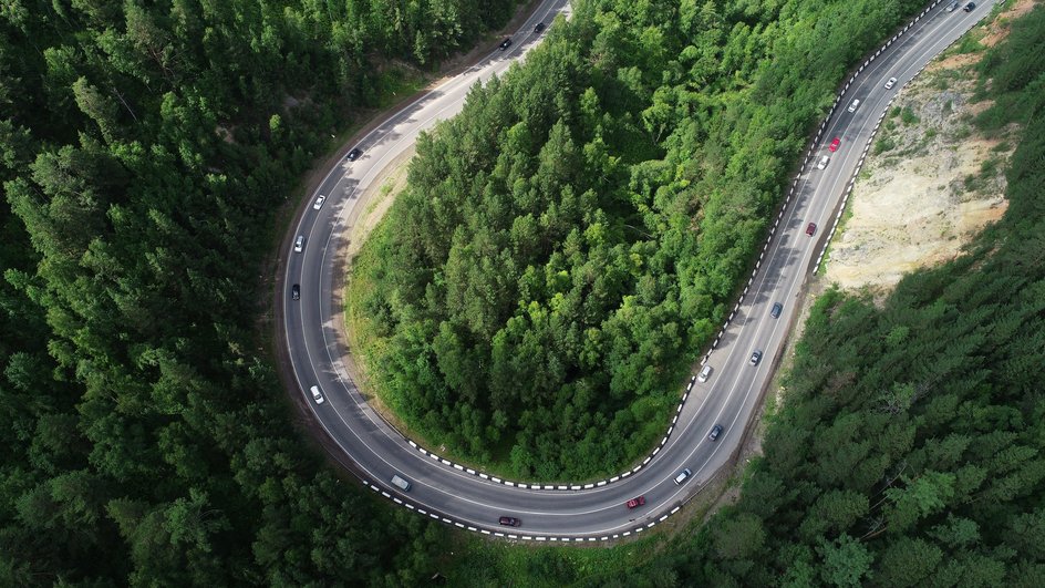 Цепочка автомобилей в тайге на трассе в окрестностях Красноярска