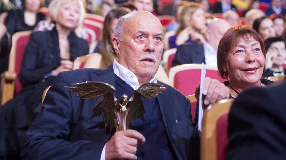 Кинорежиссер Станислав Говорухин в синем костюме сидит с наградой в зале