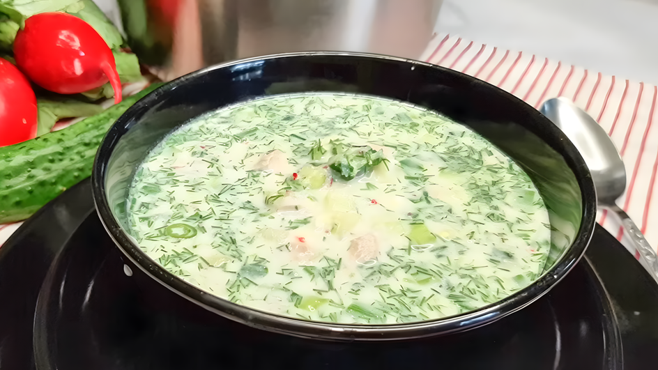Черная тарелка ПП-окрошки стоит на столе рядом с огурцами и редисом Черная тарелка ПП-окрошки стоит на столе рядом с огурцами и редисом