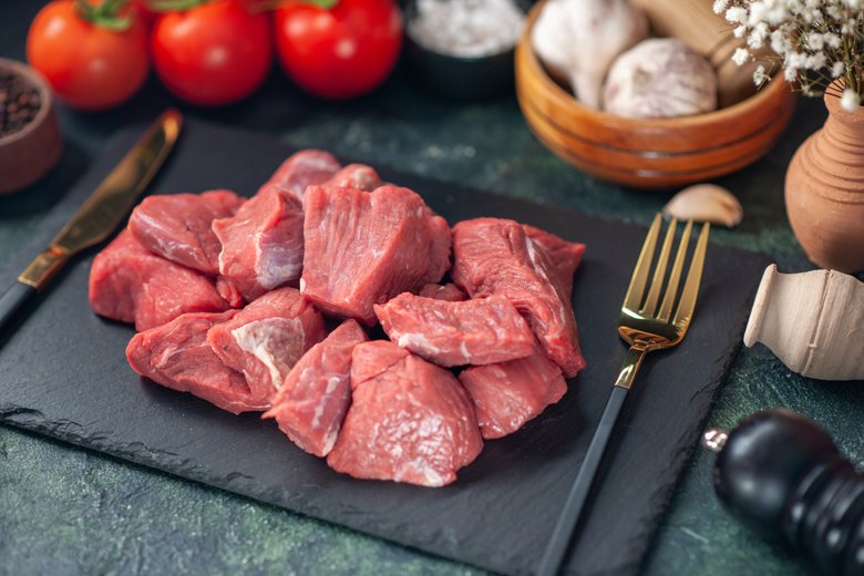 Сырое нарезанное мясо на черной доске Сырое нарезанное мясо на черной доске