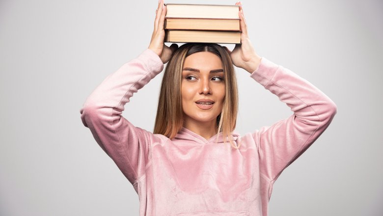 Женщина держит на голове книги для модельной осанки. Женщина держит на голове книги для модельной осанки.