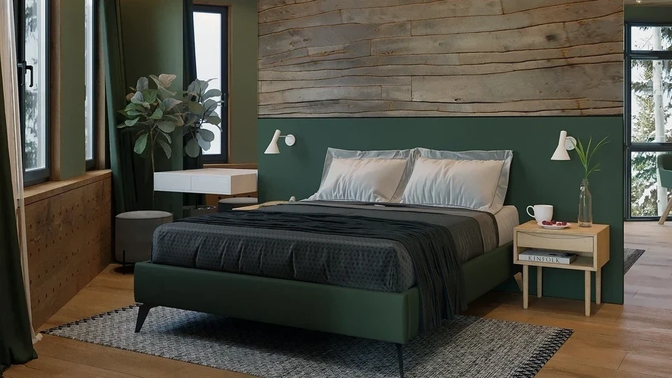 Кровать накрыта зеленым пледом на фоне коричневой стены и окна