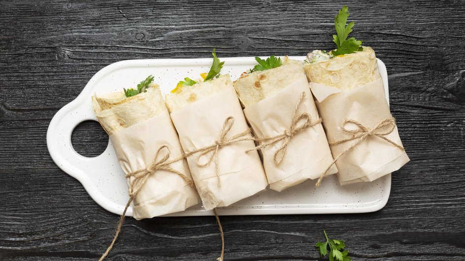 Рулеты из лаваша с крабовыми палочками, сыром и яйцом лежат на тарелке