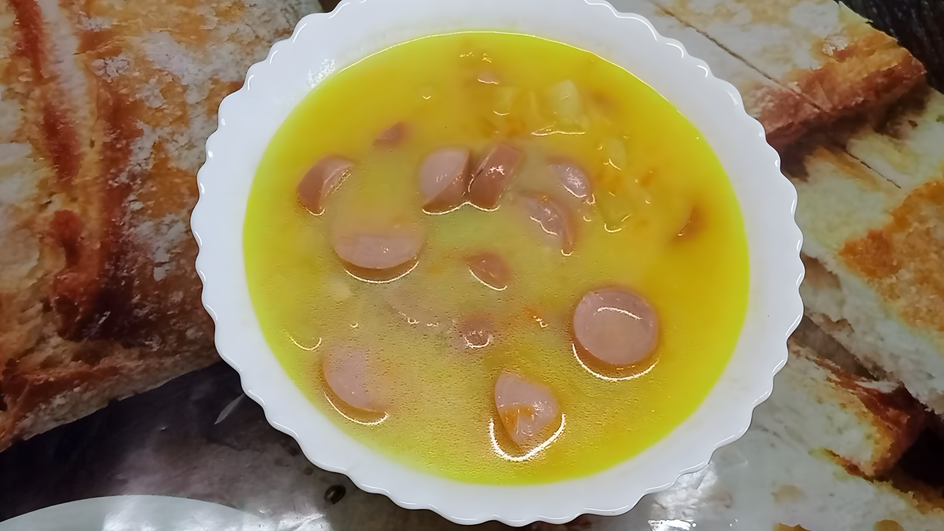 Тарелка супа с сосисками с картошкой стоит на столе Тарелка супа с сосисками с картошкой стоит на столе