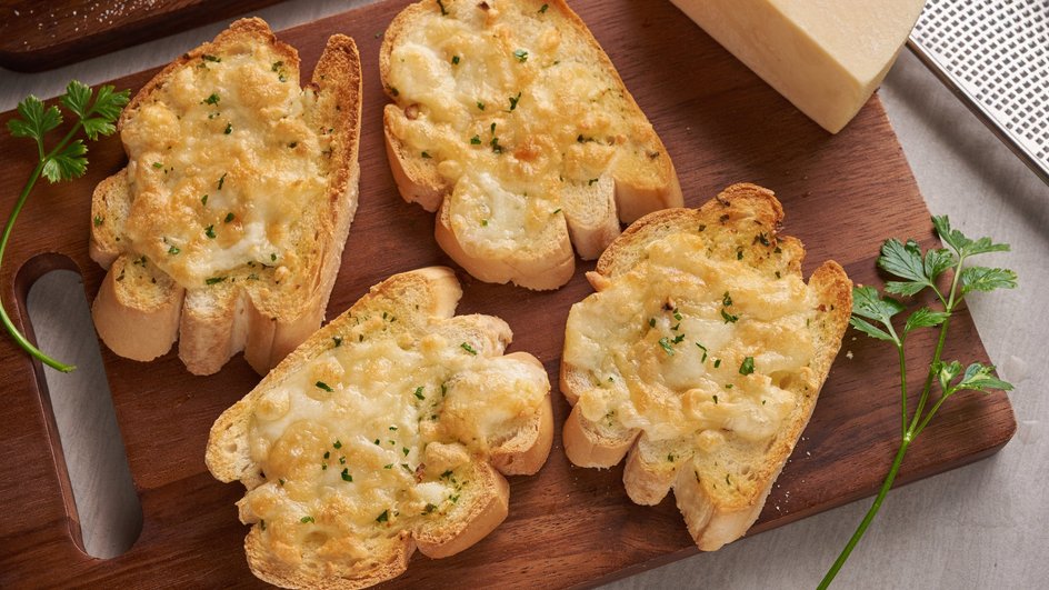 Гренки с сыром и молоком лежат на доске рядом с зеленью Гренки с сыром и молоком лежат на доске рядом с зеленью