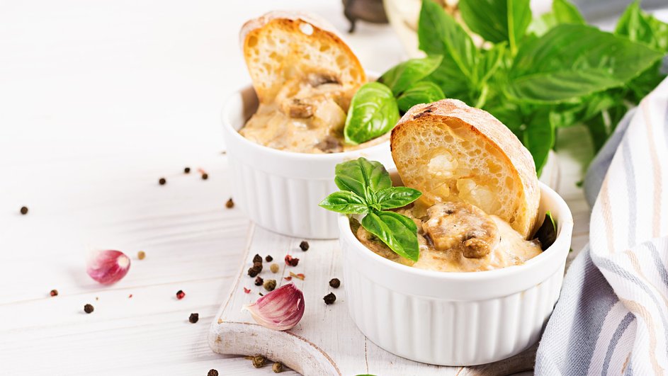 Жюльен с языком и кусочком хлеба лежит в креманке на столе рядом с ингредиентами Жюльен с языком и кусочком хлеба лежит в креманке на столе рядом с ингредиентами